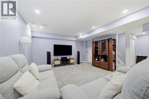 Recessed ceiling lighting, light gray wall paint, built-in shelving unit, carpet flooring, and a white staircase with a contrasting handrail - 57 Cheevers Road, Brantford, ON - Indoor