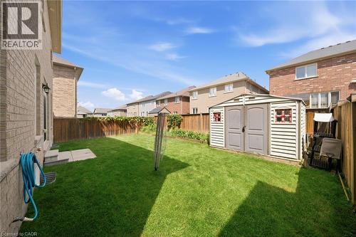 Expansive backyard featuring a green lawn, wood fence, and a storage shed with double doors - 57 Cheevers Road, Brantford, ON - Outdoor