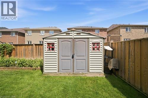Spacious backyard featuring a storage shed with dual doors, a manicured lawn, and wood fencing - 57 Cheevers Road, Brantford, ON - Outdoor