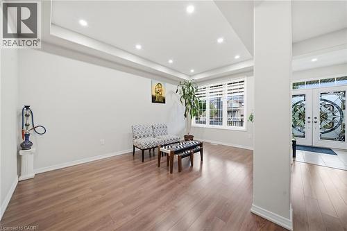 Recessed lighting, tray ceiling, wood-finish flooring, large window with blinds, and decorative glass double entry doors - 57 Cheevers Road, Brantford, ON - Indoor Photo Showing Other Room