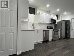Kitchen featuring white cabinetry, stainless steel appliances, wood-finish flooring, and recessed lighting - 