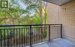 Balcony featuring black metal railings, textured flooring, and a brick exterior wall - 