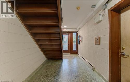 Hardwood staircase, block wall construction, terrazzo flooring, wood-paneled door, and recessed lighting - 50 Gordon Avenue, Kitchener, ON - Indoor Photo Showing Other Room