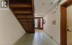 Hardwood staircase, block wall construction, terrazzo flooring, wood-paneled door, and recessed lighting - 