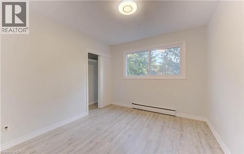 Wood-finish flooring, white walls, built-in closet with sliding doors, and a double window - 50 Gordon Avenue, Kitchener, ON - Indoor Photo Showing Other Room