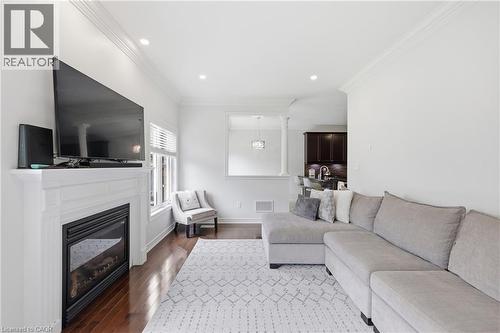 Recessed lighting, crown molding, wood-finish flooring, and a built-in fireplace with a white mantel - 738 Fourth Line, Milton, ON - Indoor Photo Showing Living Room With Fireplace