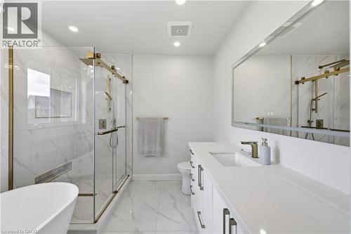 Spa-inspired primary bathroom featuring marble-look tile flooring, a freestanding soaking tub, and a spacious walk-in shower with frameless glass enclosure and brass hardware - 738 Fourth Line, Milton, ON - Indoor Photo Showing Bathroom