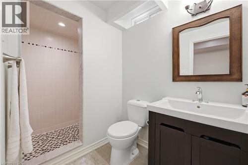 Shower stall with tiled walls and pebble-finish floor, wood-finish vanity with integrated sink, and wall-mounted mirror - 738 Fourth Line, Milton, ON - Indoor Photo Showing Bathroom