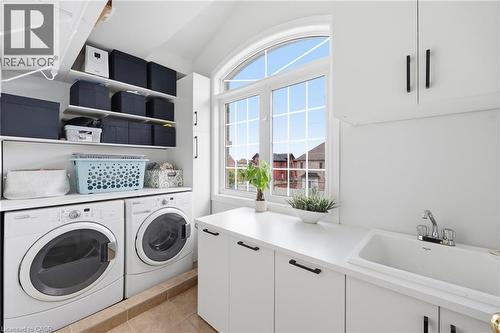 Laundry area featuring a large arched window with grid details, built-in shelving, white cabinetry with black hardware, a built-in sink, and a countertop - 738 Fourth Line, Milton, ON - Indoor Photo Showing Laundry Room