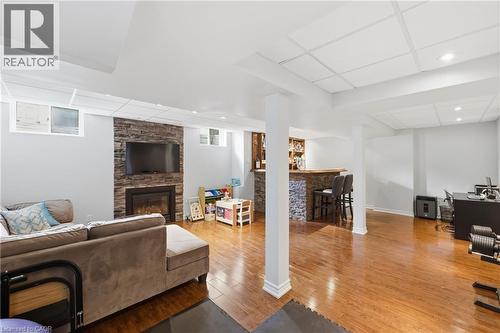Spacious finished lower level featuring hardwood-finish flooring, a stone-clad fireplace, built-in wet bar, and recessed lighting - 738 Fourth Line, Milton, ON - Indoor With Fireplace
