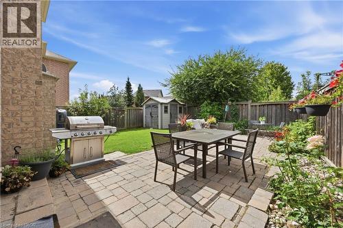 Paver patio with a dining area, manicured lawn, and wooden privacy fencing - 738 Fourth Line, Milton, ON - Outdoor
