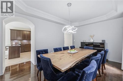 Sophisticated dining space featuring a wood-finish dining table, navy upholstered chairs with nailhead detailing, and a modern pendant light fixture - 738 Fourth Line, Milton, ON - Indoor Photo Showing Dining Room