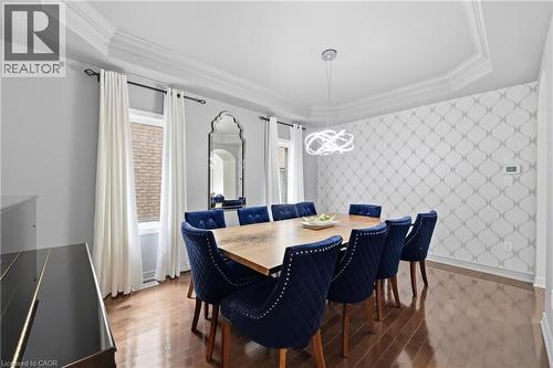 Hardwood flooring throughout, featuring crown molding, a decorative accent wall, and a modern chandelier - 738 Fourth Line, Milton, ON - Indoor Photo Showing Dining Room