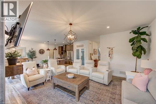 Open-concept living area featuring wood-finish flooring, recessed lighting, and a geometric chandelier - 1061 Eagletrace Drive Unit# 174, London, ON - Indoor Photo Showing Living Room