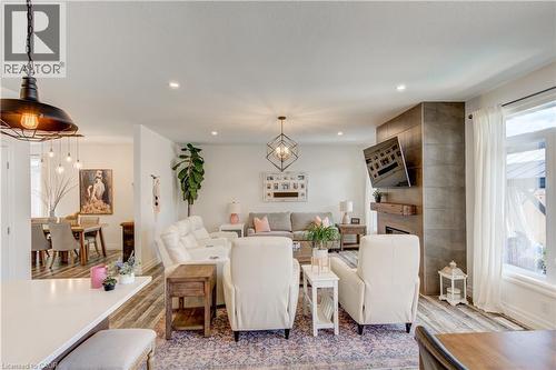 Open-concept living space with light wood-finish flooring, recessed lighting, and a prominent fireplace featuring a tile surround and wood mantel - 1061 Eagletrace Drive Unit# 174, London, ON - Indoor
