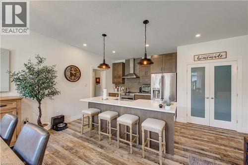 Kitchen featuring wood-finish flooring, a center island with seating, stainless steel appliances, and wood cabinetry - 1061 Eagletrace Drive Unit# 174, London, ON - Indoor Photo Showing Other Room
