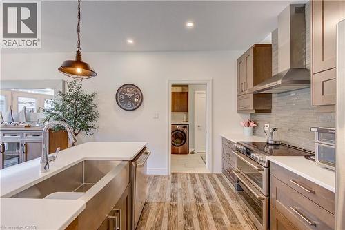 Bright kitchen featuring wood-finish flooring, white countertops, and a stainless steel farmhouse sink - 1061 Eagletrace Drive Unit# 174, London, ON - Indoor Photo Showing Kitchen With Upgraded Kitchen