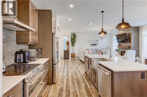 Gourmet kitchen with stainless steel appliances, wood-finish flooring, white countertops, and a tile backsplash - 1061 Eagletrace Drive Unit# 174, London, ON - Indoor Photo Showing Kitchen With Upgraded Kitchen