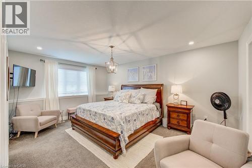 Recessed lighting, central chandelier, window with blinds, wall-mounted television, and wainscoting - 1061 Eagletrace Drive Unit# 174, London, ON - Indoor Photo Showing Bedroom