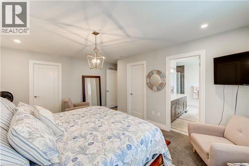 Recessed lighting, contemporary chandelier, carpeted flooring, and a doorway to a bathroom with a vanity - 1061 Eagletrace Drive Unit# 174, London, ON - Indoor Photo Showing Bedroom