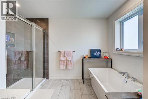 Modern bathroom featuring a glass-enclosed shower with integrated shelving, a freestanding soaking tub, and tile flooring - 1061 Eagletrace Drive Unit# 174, London, ON - Indoor Photo Showing Bathroom