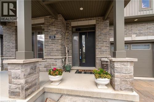 Exterior entry featuring a dark-finish door with glass inserts, stone and brick facade, and a covered porch - 1061 Eagletrace Drive Unit# 174, London, ON - Outdoor With Deck Patio Veranda