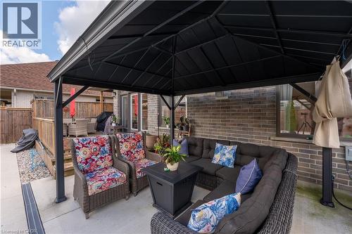 Paved patio with a black metal gazebo, brick exterior, and a wood privacy fence - 1061 Eagletrace Drive Unit# 174, London, ON - Outdoor With Deck Patio Veranda With Exterior
