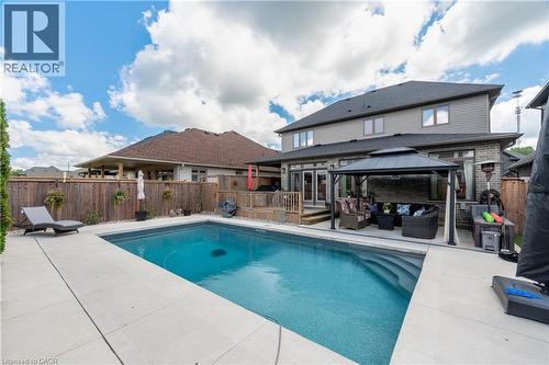 Backyard featuring an in-ground swimming pool, concrete patio, wooden privacy fence, and a gazebo with a covered seating area - 1061 Eagletrace Drive Unit# 174, London, ON - Outdoor With In Ground Pool With Deck Patio Veranda