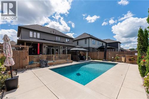 Expansive backyard featuring a rectangular swimming pool, concrete patio, a wood deck with railings, and a fenced perimeter - 1061 Eagletrace Drive Unit# 174, London, ON - Outdoor With In Ground Pool With Deck Patio Veranda