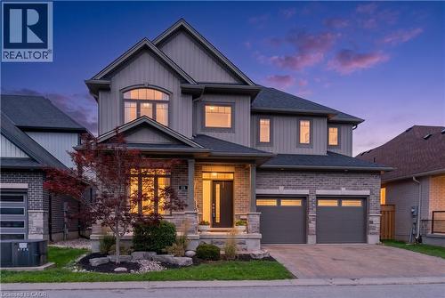 Gray siding exterior with stone accents, arched window, covered entryway, and two-car garage - 1061 Eagletrace Drive Unit# 174, London, ON - Outdoor With Facade