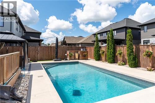 In-ground swimming pool with integrated steps, surrounded by concrete decking and a wood fence - 1061 Eagletrace Drive Unit# 174, London, ON - Outdoor With In Ground Pool With Deck Patio Veranda