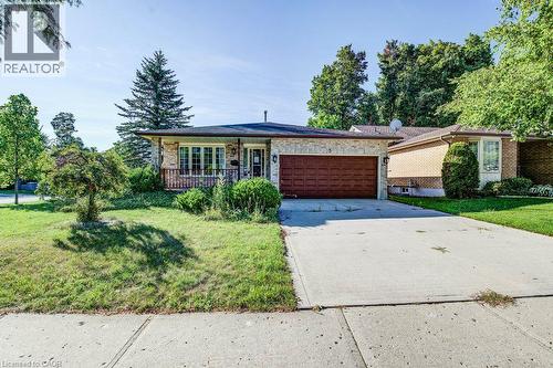 Brick facade, covered front porch, attached garage with a panel door, concrete driveway, and front lawn - 3 Cora Drive, Kitchener, ON - Outdoor