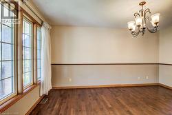 Wood-finish flooring, accent wall with chair rail molding, multi-pane windows, and a classic chandelier - 
