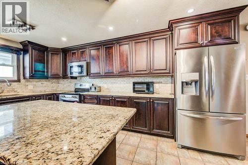 Kitchen featuring granite countertops, wood cabinetry, stainless steel appliances, and a tiled backsplash - 3 Cora Drive, Kitchener, ON - Indoor Photo Showing Kitchen With Upgraded Kitchen