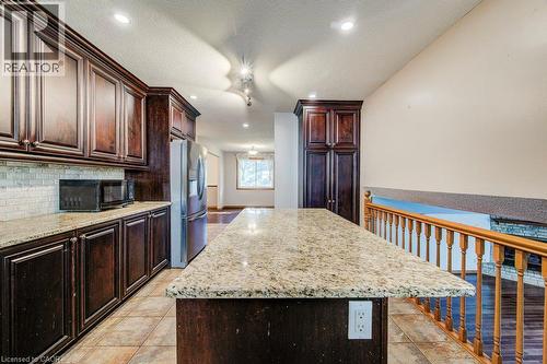 Kitchen featuring dark wood cabinetry, light-toned granite countertops, a tiled backsplash, and recessed lighting - 3 Cora Drive, Kitchener, ON - Indoor Photo Showing Kitchen