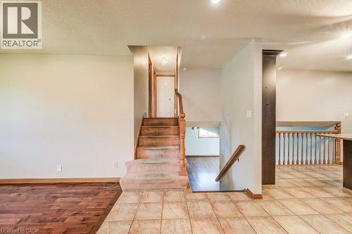 Wood-finish flooring, tiled flooring, wood banister, and recessed lighting - 3 Cora Drive, Kitchener, ON - Indoor Photo Showing Other Room