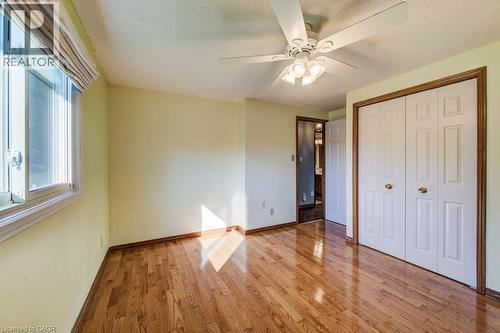 Hardwood flooring, ceiling fan with integrated lighting, white bi-fold closet doors, and wood-trim windows - 3 Cora Drive, Kitchener, ON - Indoor Photo Showing Other Room