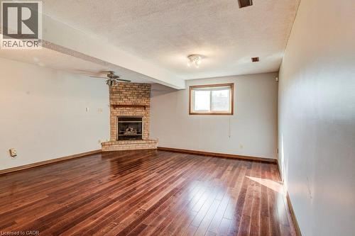 Wood-finish flooring, brick fireplace, window with wood trim, ceiling fan, and overhead lighting - 3 Cora Drive, Kitchener, ON - Indoor With Fireplace