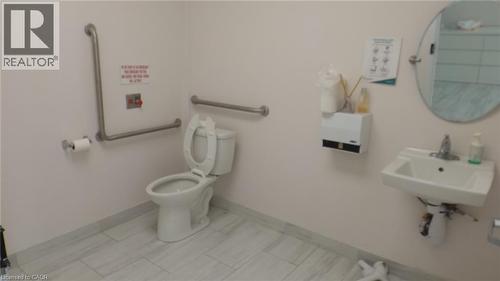 Ceramic tile flooring, wall-mounted sink, oval mirror, and grab bars - 64 Frederick Drive Unit# 101, Guelph, ON 