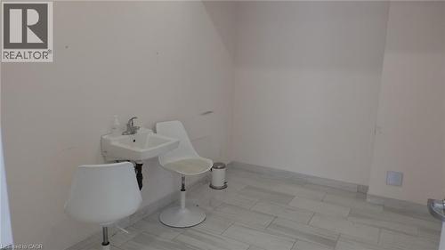 Wall-mounted sink with chrome faucet, light-toned wall finish, and tiled flooring - 64 Frederick Drive Unit# 101, Guelph, ON 