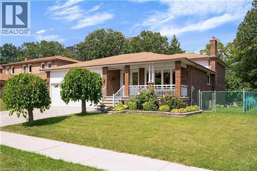 Brick exterior with a covered front porch featuring white railings, a front-facing attached garage, and a chain-link fence enclosing a portion of the yard - 2535 Privet Crescent, Mississauga, ON - Outdoor