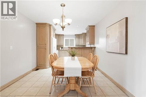 Tiled flooring, overhead chandelier, light wood-finish cabinetry, and white window shutters - 2535 Privet Crescent, Mississauga, ON - Indoor Photo Showing Dining Room