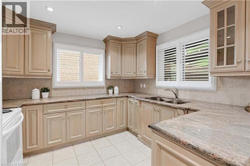 U-shaped kitchen featuring light wood-finish cabinetry, solid surface countertops, a tile backsplash, and recessed lighting - 2535 Privet Crescent, Mississauga, ON - Indoor Photo Showing Kitchen With Double Sink