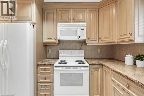 Kitchen featuring light wood-finish cabinetry, a tile backsplash, and a built-in microwave - 2535 Privet Crescent, Mississauga, ON - Indoor Photo Showing Kitchen