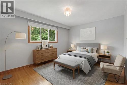 *VIRTUALLY STAGED* Light-filled room featuring wood-finish flooring, a window with wood trim, and a ceiling-mounted light fixture - 2535 Privet Crescent, Mississauga, ON - Indoor Photo Showing Bedroom