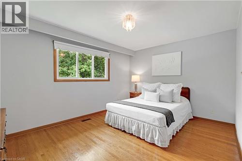 Hardwood flooring, light gray wall finishes, a wood-framed window, and a ceiling-mounted light fixture - 2535 Privet Crescent, Mississauga, ON - Indoor Photo Showing Bedroom