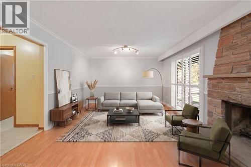 *VIRTUALLY STAGED* Spacious living area featuring wood-finish flooring, a stone fireplace, crown molding, and large windows with plantation shutters - 2535 Privet Crescent, Mississauga, ON - Indoor Photo Showing Living Room With Fireplace