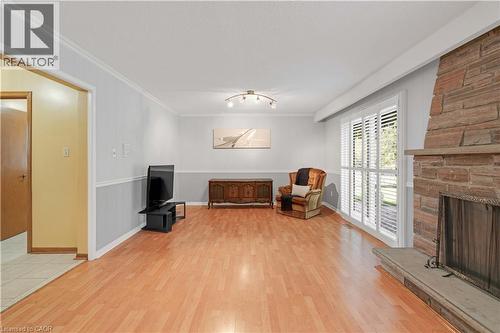 Wood-finish flooring throughout, board and batten paneling, stone-clad fireplace with hearth, and a sliding glass door with plantation shutters - 2535 Privet Crescent, Mississauga, ON - Indoor With Fireplace