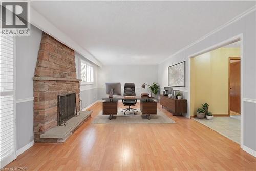 *VIRTUALLY STAGED* Stone-clad fireplace with a stone hearth, wood-finish flooring, and white window shutters - 2535 Privet Crescent, Mississauga, ON - Indoor With Fireplace