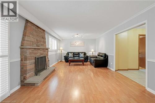 Spacious living area featuring wood-finish flooring, a stone fireplace, and a light-colored two-tone wall treatment - 2535 Privet Crescent, Mississauga, ON - Indoor Photo Showing Living Room With Fireplace